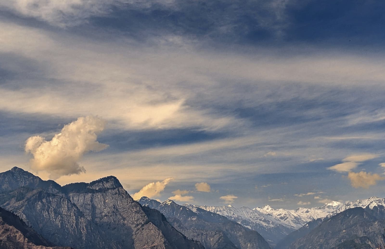 Clouds over the steep, snow-capped ridges of the Parvati Valley seen from Ratocha village