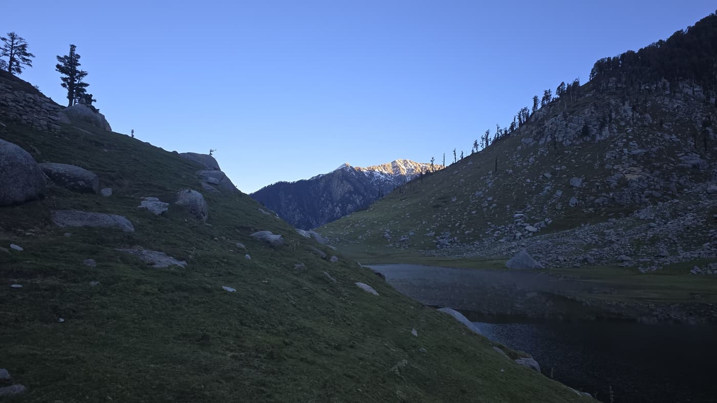 The alpine Kareri Lake in a green valley below the Dhauladhar