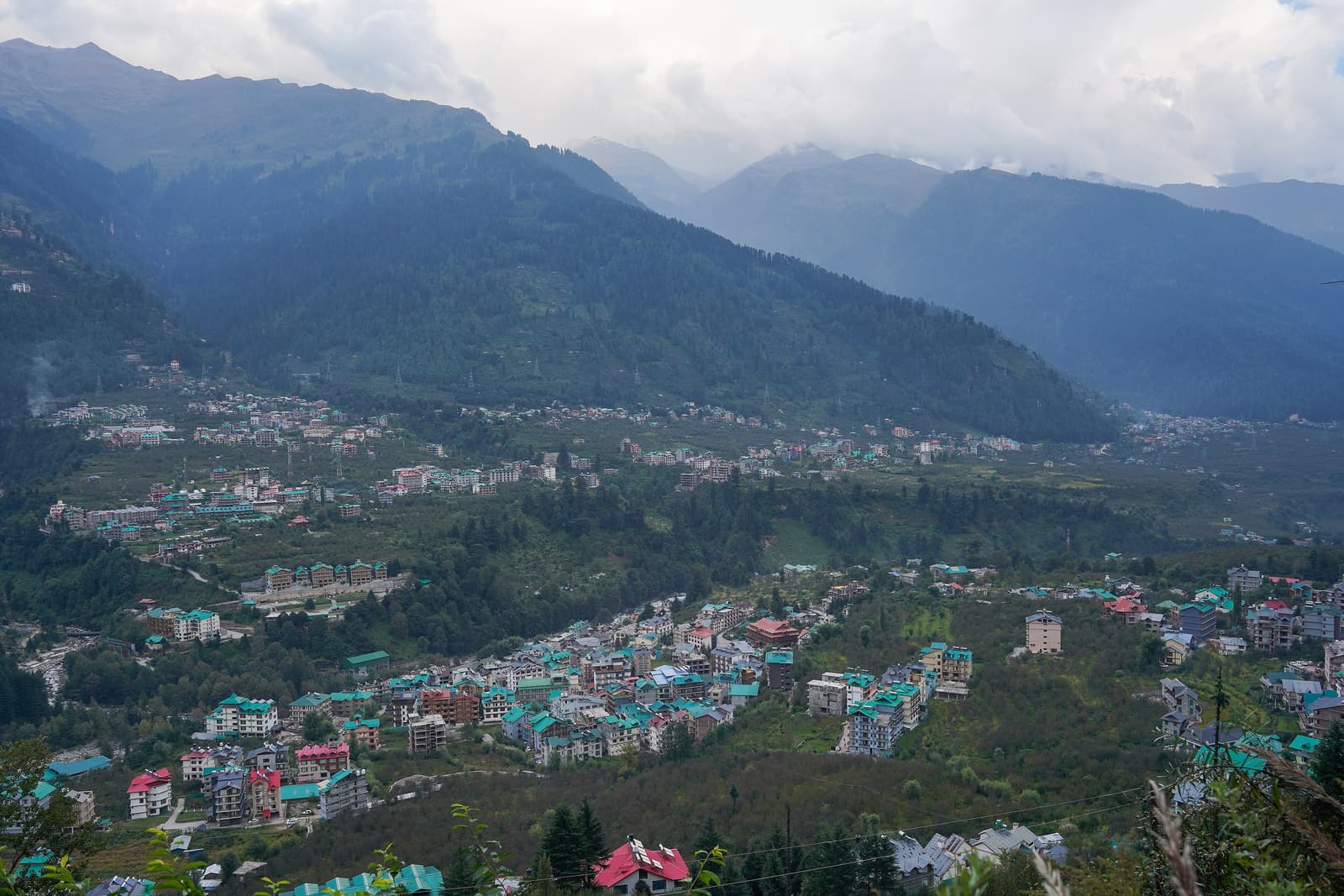 Manali town spread across the forested Beas valley seen from the hillside above