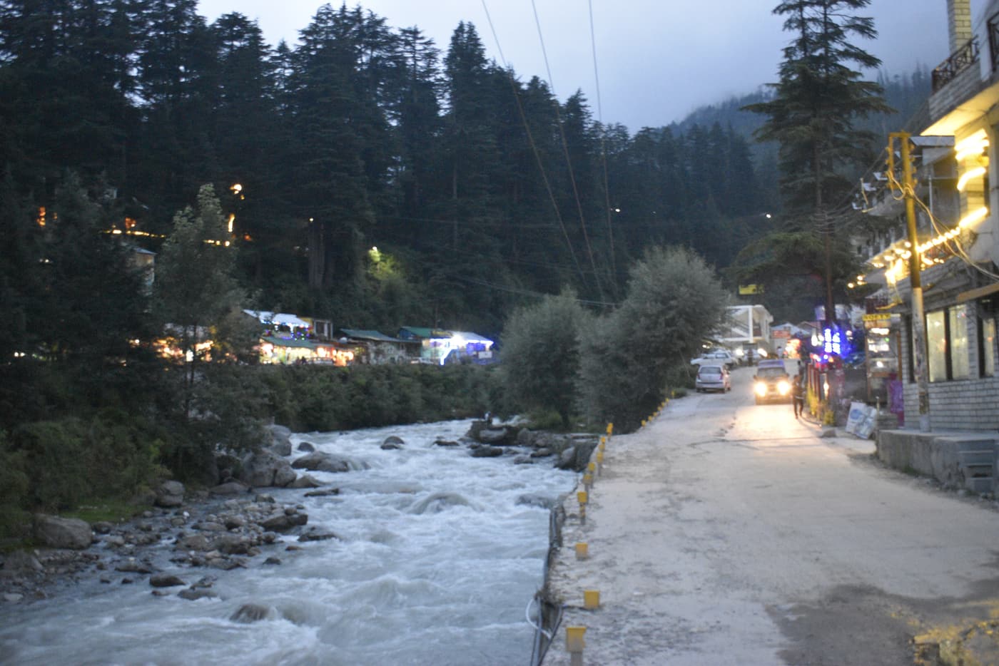 The Manalsu stream and lane through Old Manali under deodar trees at dusk
