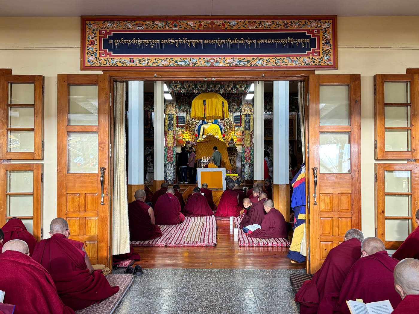 Monks in maroon robes praying inside the Namgyal Monastery, Dharamshala